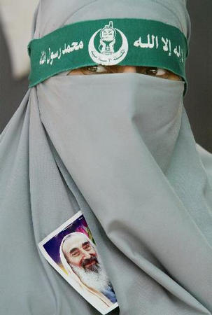 A veiled Palestinian woman wears a picture of Hamas spiritual leader Ahmed Yassin at a mourning tent, Gaza City, March 24, 2004.