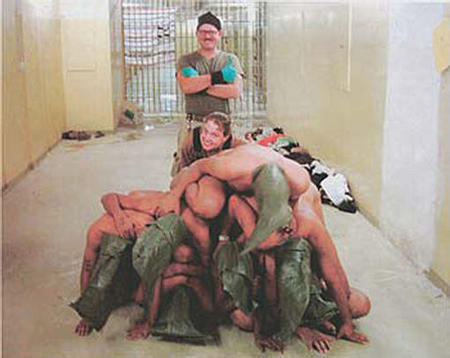 American soldiers stand behind a pyramid of naked Iraqi prisoners at the Abu Ghraib prison near Baghdad, Iraq in this undated photo released on April 30, 2004.