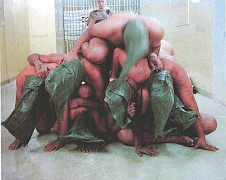 An American soldier stands behind a pyramid of naked Iraqi prisoners at the Abu Ghraib prison near Baghdad, Iraq in this undated photo released on April 30, 2004.