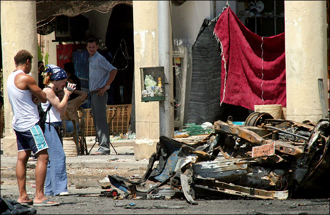 Just a day after the explosions, visitors, undeterred by terrorist attacks, photograph a car destroyed by a bomb in the town market, Sharm A-Sheik, July 25, 2005.