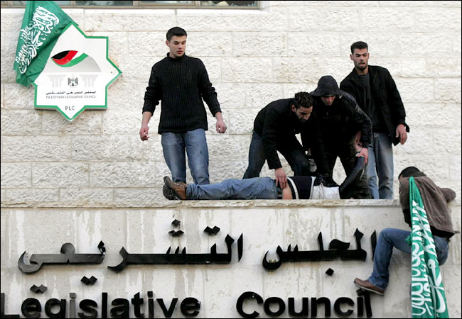 After winning elections, Hamas supporters raise their flag over the Palestinian parliament, where a man was hurt during a clash with rivals, Ramallah, January 26, 2006.