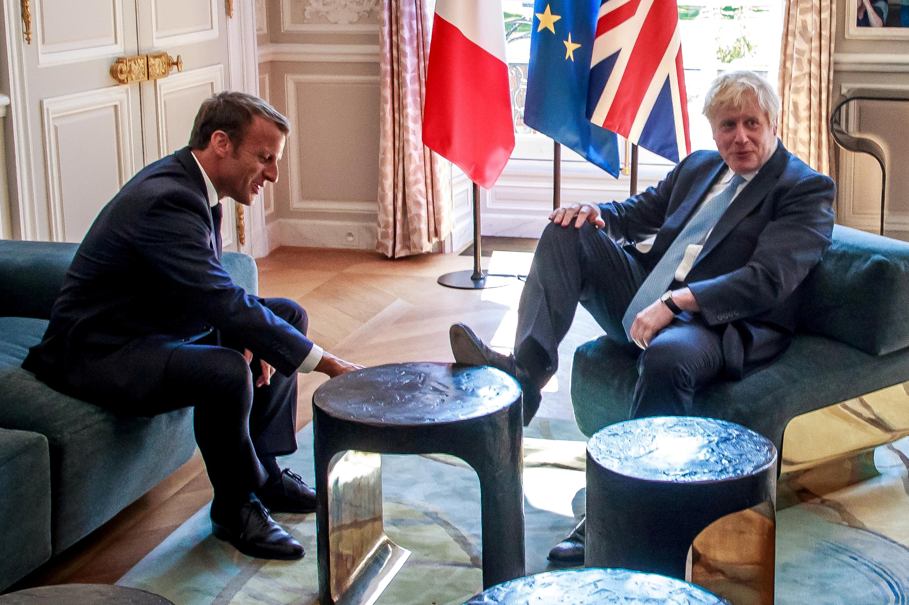 UK Prime Minister Boris Johnson puts his foot on table as French President Emmanuel Macron watching in, Palace of l'Élyse Paris, August 22, 2019.