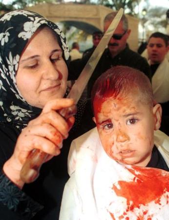 A Shiite Muslim woman holds a three-year old boy whose forehead was cut during a ceremony in Nabatiyeh, Lebanon, March 24, 2002, Ashoura Day, the Shiite Muslim religious festival which marks the AD 680 battle in which Imam Hussein, the grandson of Islam's Prophet Mohammed, was killed.