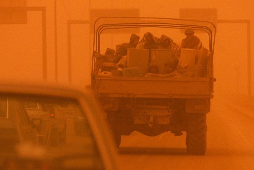 Iraqi army recruits ride in the back of a truck on a highway around Baghdad, as a fierce sandstorm sweeps through the area, March 26, 2003.