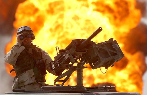 A U.S. soldier looks through a pair of binoculars as a fire in the Rumeila oil field burns in the background, southern Iraq, March. 30, 2003.