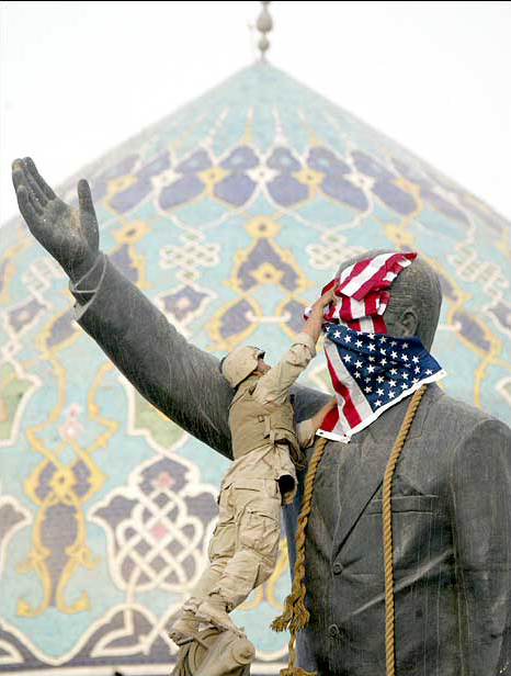 Cpl. Edward Chin of the 3rd battalion, 4th Marines regiment, set up the American flag on the face of the giant Saddam Hussein's statue before pulling it down, central Baghdad, April 9, 2003.