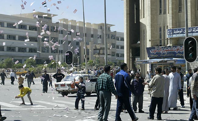 Iraqis throw money in the air in celebration, center of Mosul, April 11, 2003.