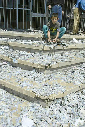 An Iraqi boy plays with Iraqi notes, front of a bank in the center of Mosul after widespread looting occurred there, April 11, 2003.
