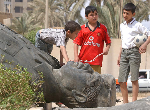 Iraqi kids examine a toppled statue of the Iraqi leader Saddam Hussein, Baghdad, April 12, 2003.