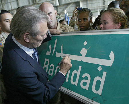 US Secretary of Defense Donald Rumsfeld signs a Baghdad road sign at the request of a US soldier, Baghdad International Airport, April 30, 2003.
