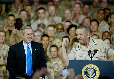 General Tommy Franks pumps his fist and arm as he introduces U.S. President George W. Bush on stage at Camp As-Sayliyah, Doha, June 5, 2003.