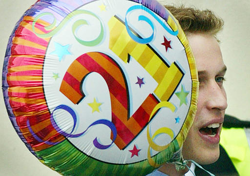 Britain's Prince William with a balloon given to him by a member of the public, as he leaves NASH (Newport Action for Single Homeless) in Newport, Wales, June 19, 2003. The Prince, accompanied by his father Prince Charles, was visiting Wales as part of the celebrations marking his 21st birthday.