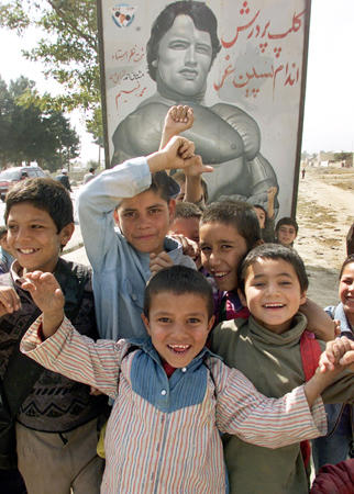 Afghan children celebrate in front of a billboard featuring Hollywood action hero Arnold Schwarzenegger as 'Arnold, the American man, the bodybuilder,' hours after he was elected as the new governor of California, Kabul, October 8, 2003