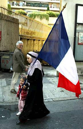 A Muslim woman walks with a French flag during with a demonstration against far-right National Front candidate Jean-Marie Le Pen, Nice, May 1, 2002.