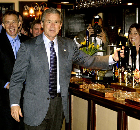 U.S. President George W. Bush jokes as he pretends to pour a pint of beer alongside British Prime Minister Tony Blair at the Dun Cow pub in Sedgefield, Tony Blair's constituency, Northern England, to which Bush travelled to meet the locals and conduct a private meeting, November 21, 2003.