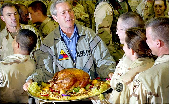 U.S. President George W. Bush holds up a turkey platter for U.S. troops during his surprise visit for Thanksgiving at a military base at Baghdad International Airport, November 27, 2003.