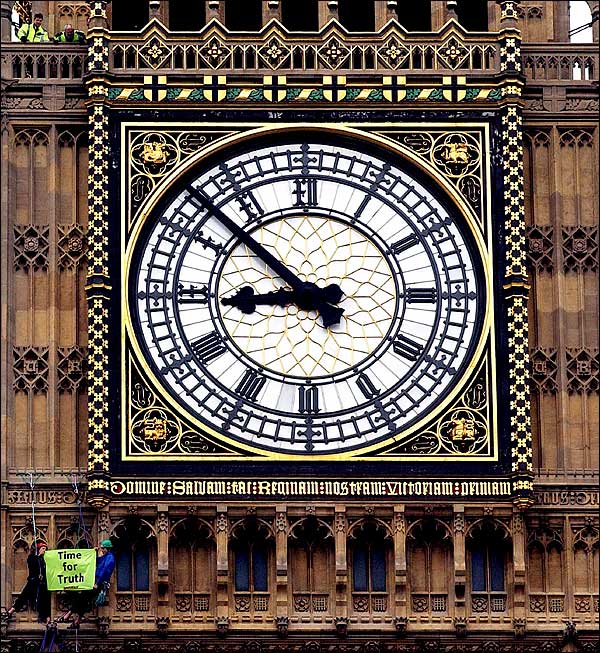 Two Greenpeace climbers hold a small banner, protesting against the Iraq war, after scaling St. Stephen's Tower (the Big Ben clock tower) at the Houses of Parliament, London, March 20, 2004.
