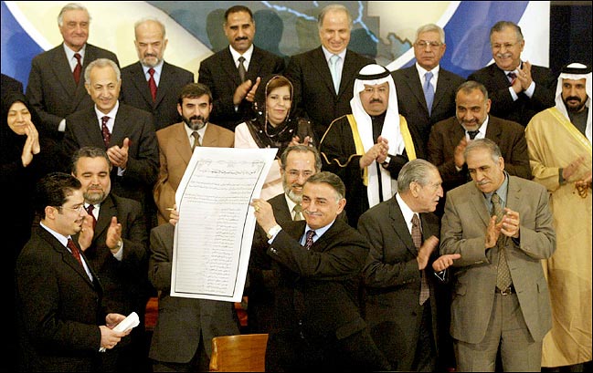 Yonadem Kanna, of the Assyrian Democratic Movement, displays the interim constitution after the 25 Iraqi council members finished signing it, Baghdad, March 8, 2004.