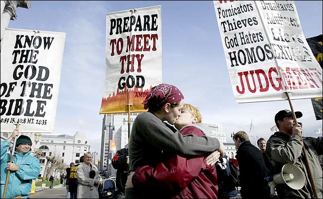 The newlyweds Emily Renard, left, and Sara Graham kiss as members of a religious group, Repent America, express their opposition to gay marriage, San Francisco, February, 2004.
