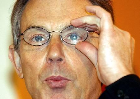 Prime Minister Tony Blair adjusts his glasses during his speech to the Public Services Summit in Chandler's Cross, London, January 29, 2004.