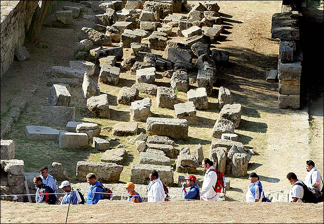 Olympic men's shotput finalists walk through the ruins of ancient Olympia on their way to competing in the shot-put, the first Olympic event held at the site in nearly 16 centuries, in the 2004 Athens Olympic Games, Ancient Olympia, Greece, August 18, 2004.