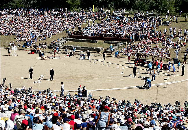 Spectators sat on the grassy hillside to watch the qualifying round of the 2004 Athens Olympics women's shot-put event which was held inside the ancient stadium used for Olympic competition for the first time in nearly 16 centuries, in the 2004 Athens Olympic Games, Ancient Olympia, Greece, August 18, 2004.