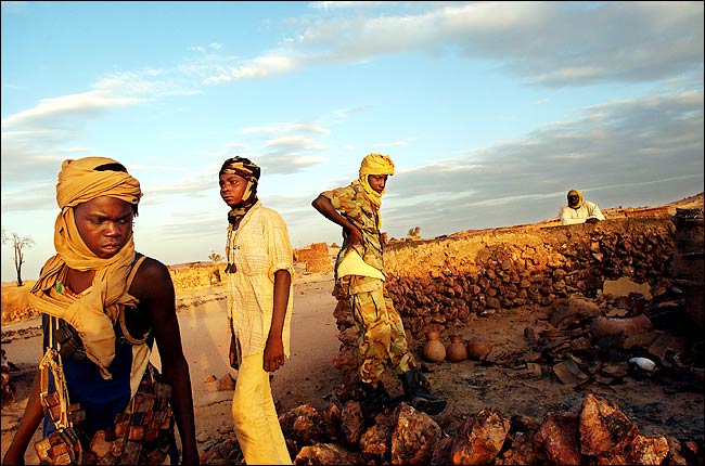 Sudanese Liberation Army soldiers look over the remains of a village burned-out by Janjaweed Arab militias, western Darfur, Sudan, August 2004.