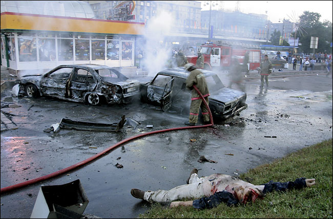 Firefighters extinguish a fire in a car near the body of a victim of an Islamic suicide bombing, Moscow, August 31, 2004.