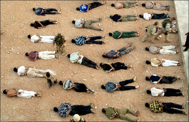 Marines stood guard over some of the 29 captives taken in a night raid of a suspected Mahdi Army haven in Kufa, Iraq, August 21, 2004.