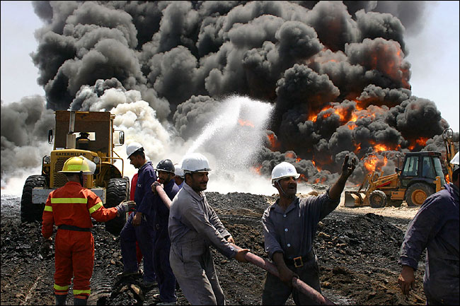 South Oil Company workers try to control a fire caused by sabotage to the pipeline connecting the oil fields of Rumaila and Zubair, Iraq, August 29, 2004.