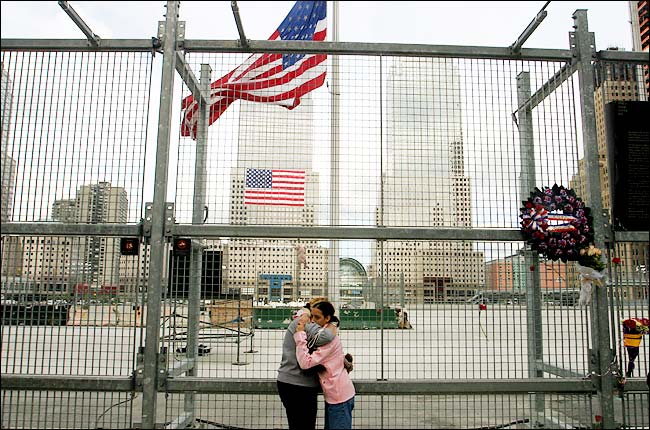 Two women embrace after the ceremonies ended at ground zero, the Church Street side of the fence surrounding the trade center site, New York, at noon, September 10, 2004.