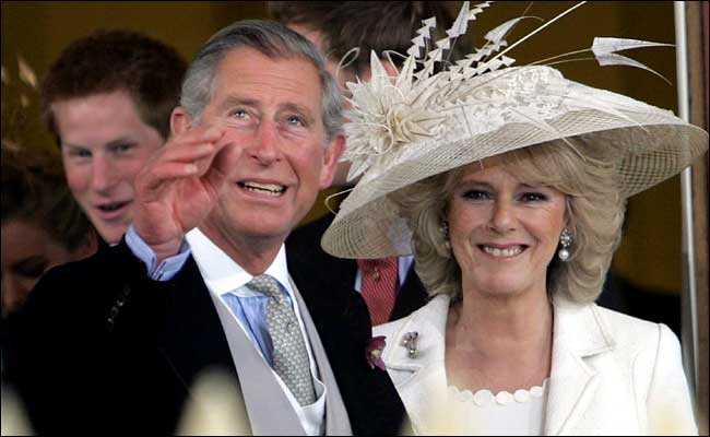 Prince Charles and Camilla, Duchess of Cornwall, greet the crowd that gathered outside Windsor Castle's St. George's Chapel after having their wedding blessed, while Charles' son Prince Harry peers from behind, April 9, 2005.