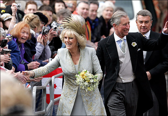 Prince Charles and Camilla, Duchess of Cornwall, greet the crowd that gathered outside Windsor Castle's St. George's Chapel after having their wedding blessed, while Charles' son Prince Harry peers from behind, April 9, 2005.