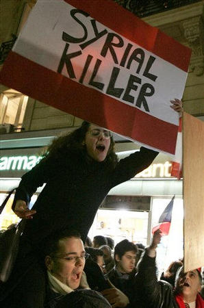 A protester holds a banner reading 'Syrial Killer' as members of Paris-based Lebanese opposition movements shout slogans hostile to Syria during a gathering for an anti-Syrian protest near the Lebanese embassy in Paris, February 21, 2005.