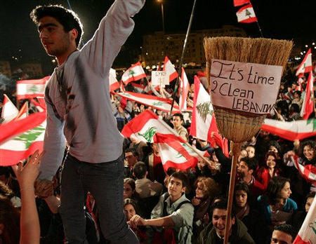 Lebanese opposition protesters wave national flags and one carries a broom with an anti-Syria slogan, during their daily demonstration against Syria in Beirut, Lebanon, March 4, 2005.