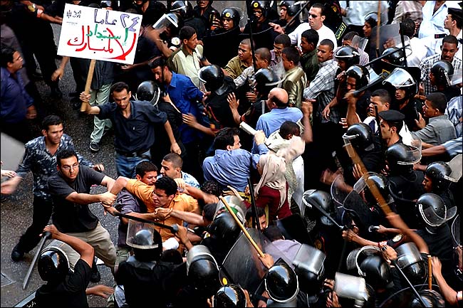 The police battle protesters as one carries a sign calling for an end to '24 years of oppression' under President Hosni Mubarak, Cairo, July 30, 2005.