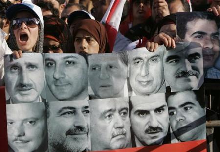 A Lebanese woman shouts anti-Syrian slogans as she stands next to other protesters holding a poster showing slain Lebanese leaders whose assassinations are blamed on Syria, during the funeral of prominent anti-Syrian Christian politician Pierre Gumayel, at the Martyrs square, Beirut, Lebanon, November 23, 2006.