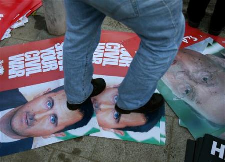 A Lebanese man walks on posters showing Syrian President Bashar al-Asad, left, and Lebanese politician Michel Aoun, now ally of Hezbollah, in Martyrs' square where mourners gathered before the funeral of assassinated Christian politician Pierre Gumayel, Beirut, Lebanon, November 23, 2006.