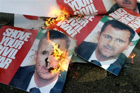 Posters carrying the portrait of Syrian President Bashar al-Asad and saying 'Shove your Civil War' burn, in Martyrs' square where mourners gathered before the funeral of assassinated Christian politician Pierre Gumayel, Beirut, Lebanon, November 23, 2006.