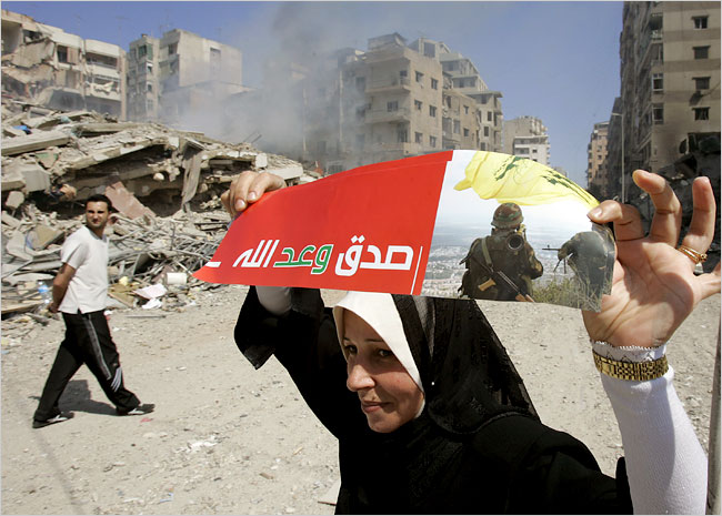 In wrecked southern Beirut, a woman raises a flyer says 'God's promise has been fulfilled,' August 14, 2006.