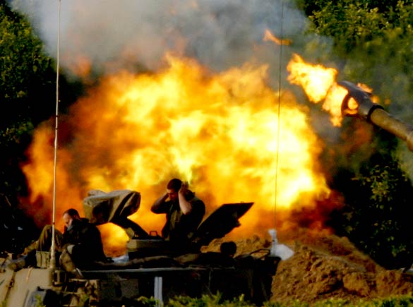 On the tweny-first day of Israels war against Gaza, an Israeli soldier covers his ears as a mobile artillery unit fires a shell towards northern Gaza from its position outside the Gaza Strip, January 16, 2009.