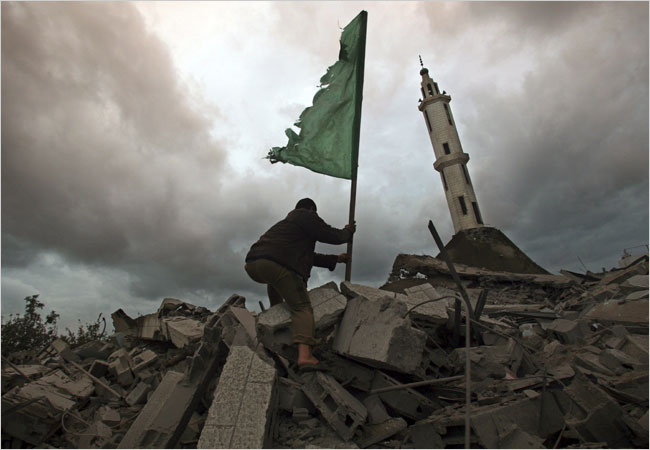 On the fifth day of Israel’s massive attack on Hamas sites throughout Gaza in retaliation for the recent rocket fire from the area, a Hamas member puts a Hamas flag on the remains of the destroyed Abu Hanifa mosque in the Tal al Hawa area, south of Gaza City, December 31, 2008.
