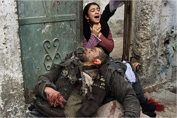 On the thirteenth day of Israel’s war against Gaza, a Palestinian woman kneels beside the bodies of relatives, moments after they were killed in an Israeli missile strike outside their home in Beit Lahiya, northern Gaza Strip, January 8, 2009.