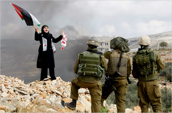 On the thirteenth day of Israels war against Gaza, a Palestinian girl stands in front of Israeli soldiers during a protest in the West Bank village of Bilin, near Ramallah, January 8, 2009.