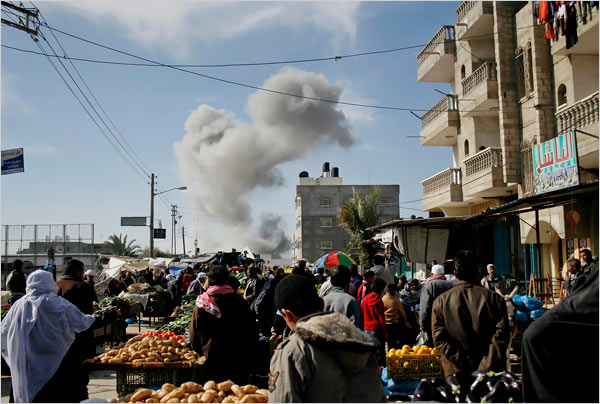 On the eighteenth day of Israels war against Gaza, Palestinians buy food in the street as smoke rose following explosions caused by Israeli military operations, Rafah, January 13, 2009.