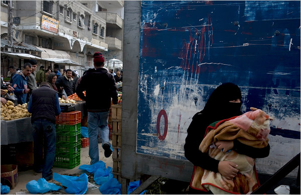 On the twenty-first day of Israel’s war against Gaza, a veiled woman holds her baby in an outdoor market, Rafah, January 16, 2009.