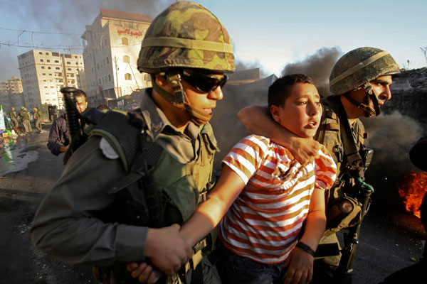 As Palestinians gather for a prayer service near the city's Lion's Gate and hurl rocks and bottles at Israeli police, Israeli border police officers detain a Palestinian youth during clashes in the Shuafat refugee camp, east Jerusalem, October 5, 2009.