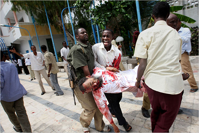 The body of the Somali Minister of Education Ibrahim Hassan Cadow is carried away from the scene of a suicide bomb attack carried by a suicide bomber disguised as a veiled woman, during a university student graduation ceremony at a local hotel in Mogadishu, December 4, 2009.