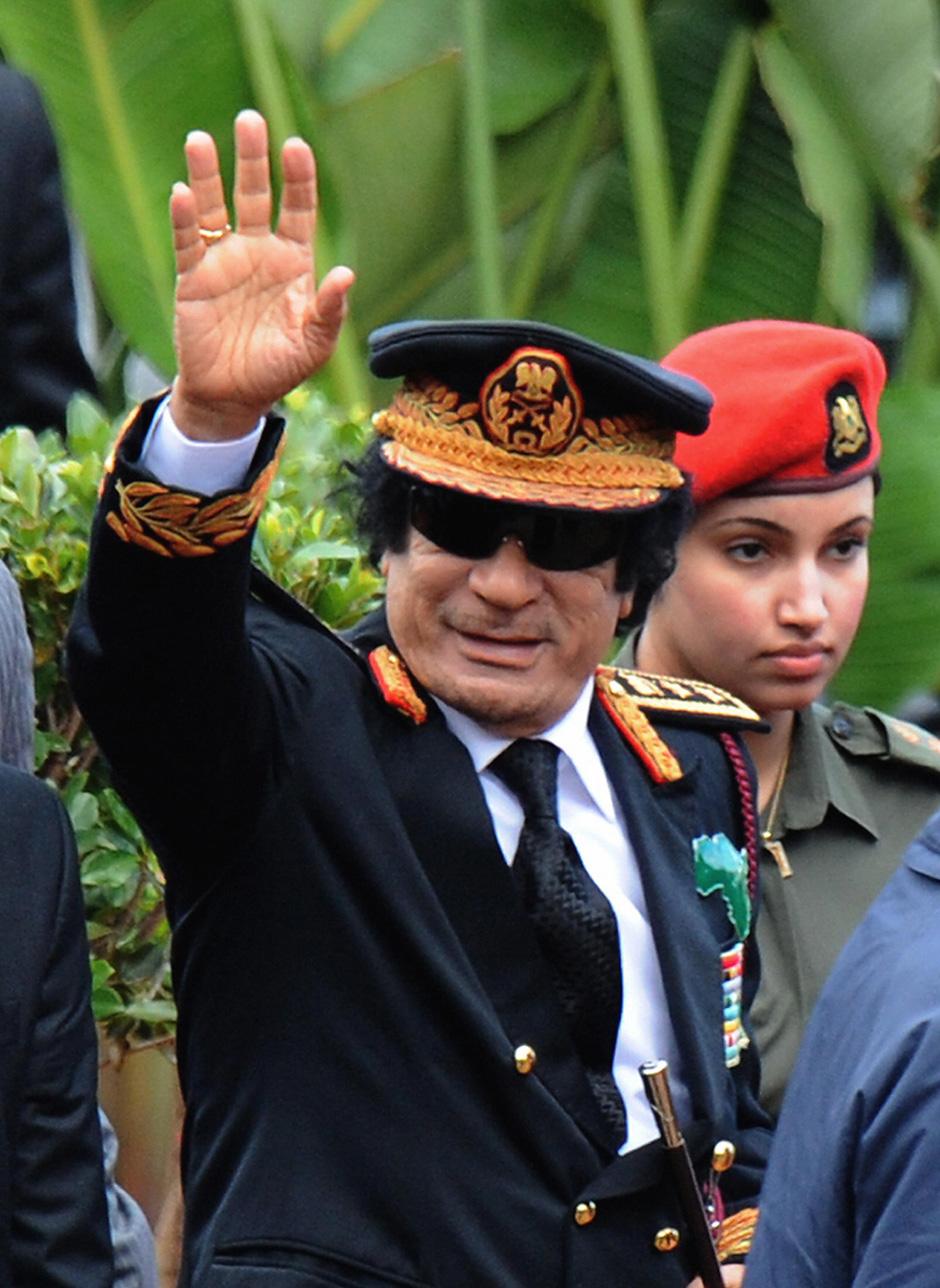 Libyan leader Muammar Al-Qaddafi, escorted by one of his female bodyguards, greets the crowd at the inauguration ceremony of South Africa's newly elected president Jacob Zuma, Pretoria, May 9, 2009.