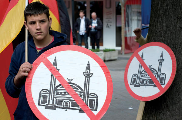 A German youth carries a national flag and an anti-Islamic sign during a march in opposition to the building of a mosque in Cologne, Germany, 2009.